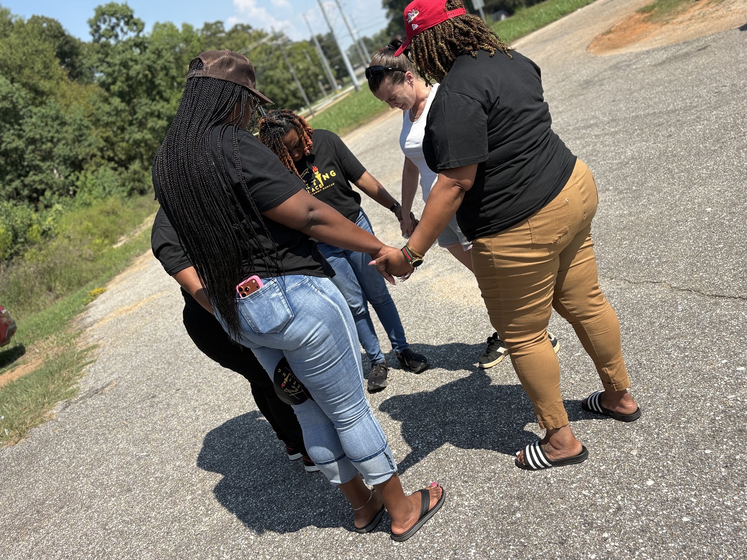 Outreach team members joining hands in prayer outdoors