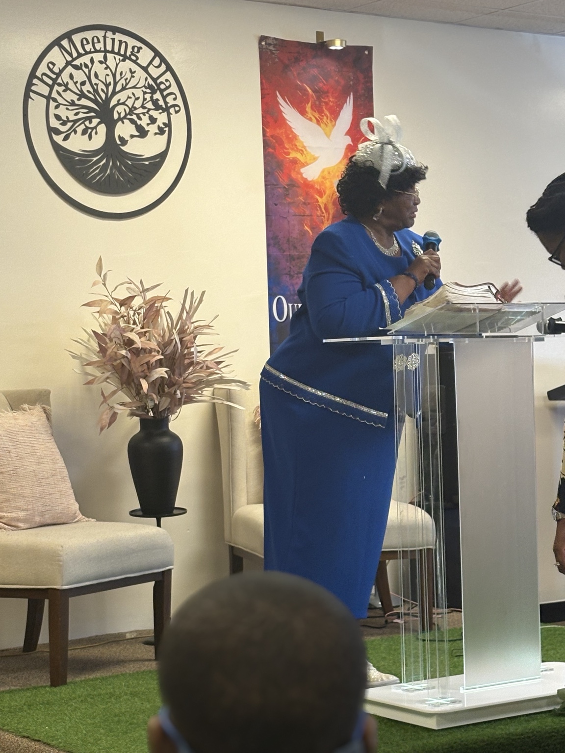 A minister in blue speaking at the pulpit during a Meeting Place service
